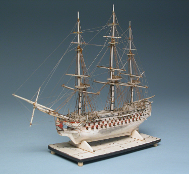   PRISONER-OF-WAR MINIATURE BONE MODEL OF A SHIP-OF-THE-LINE, circa 1800, four decker with 120 guns, carved and polychromed female figurehead and stern-castle; mounted on bone and ebony base. Height 7  in. Length 8  in.
